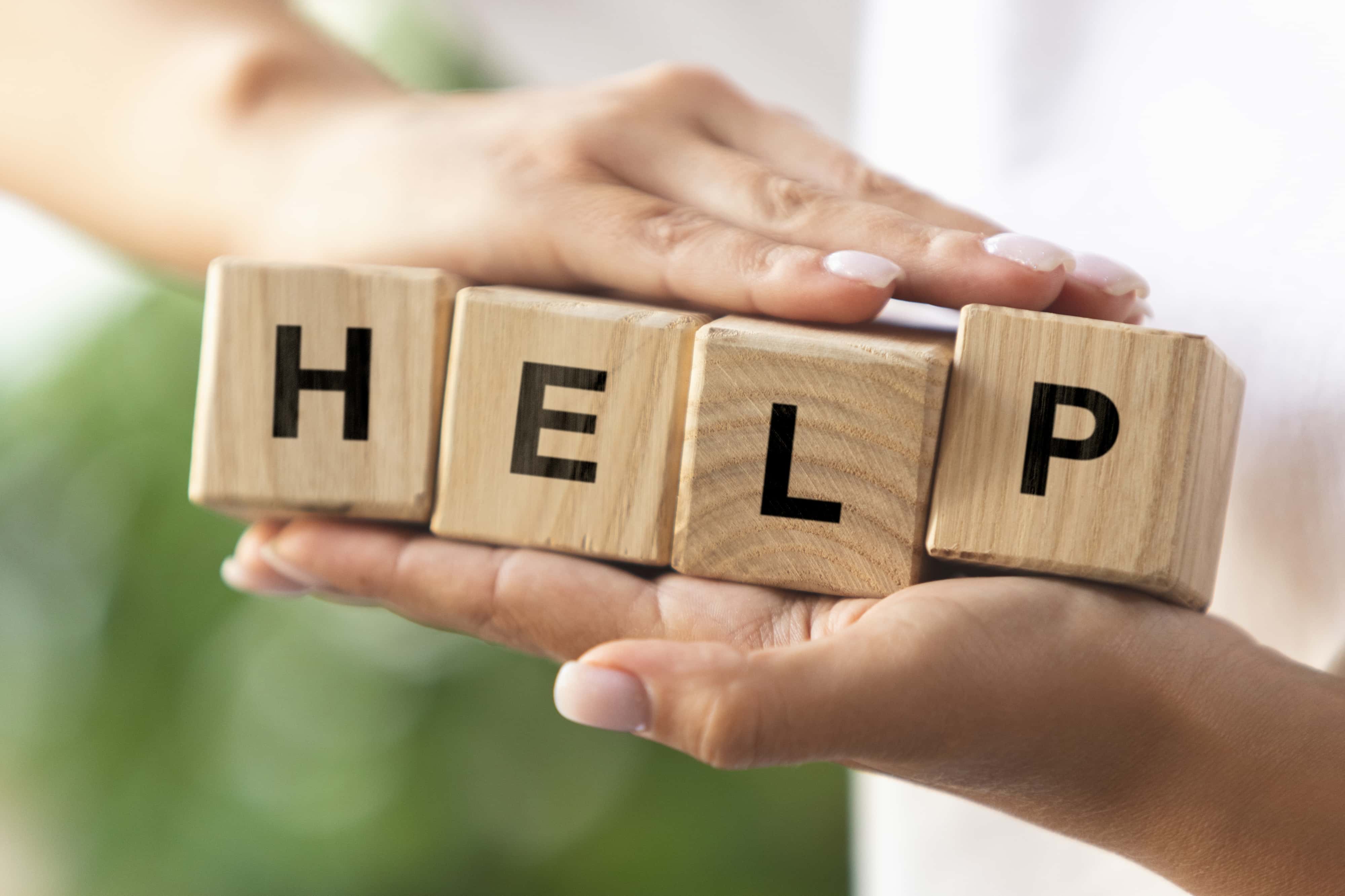 female-hands-holding-wooden-cubes-blocks-word-help.jpg