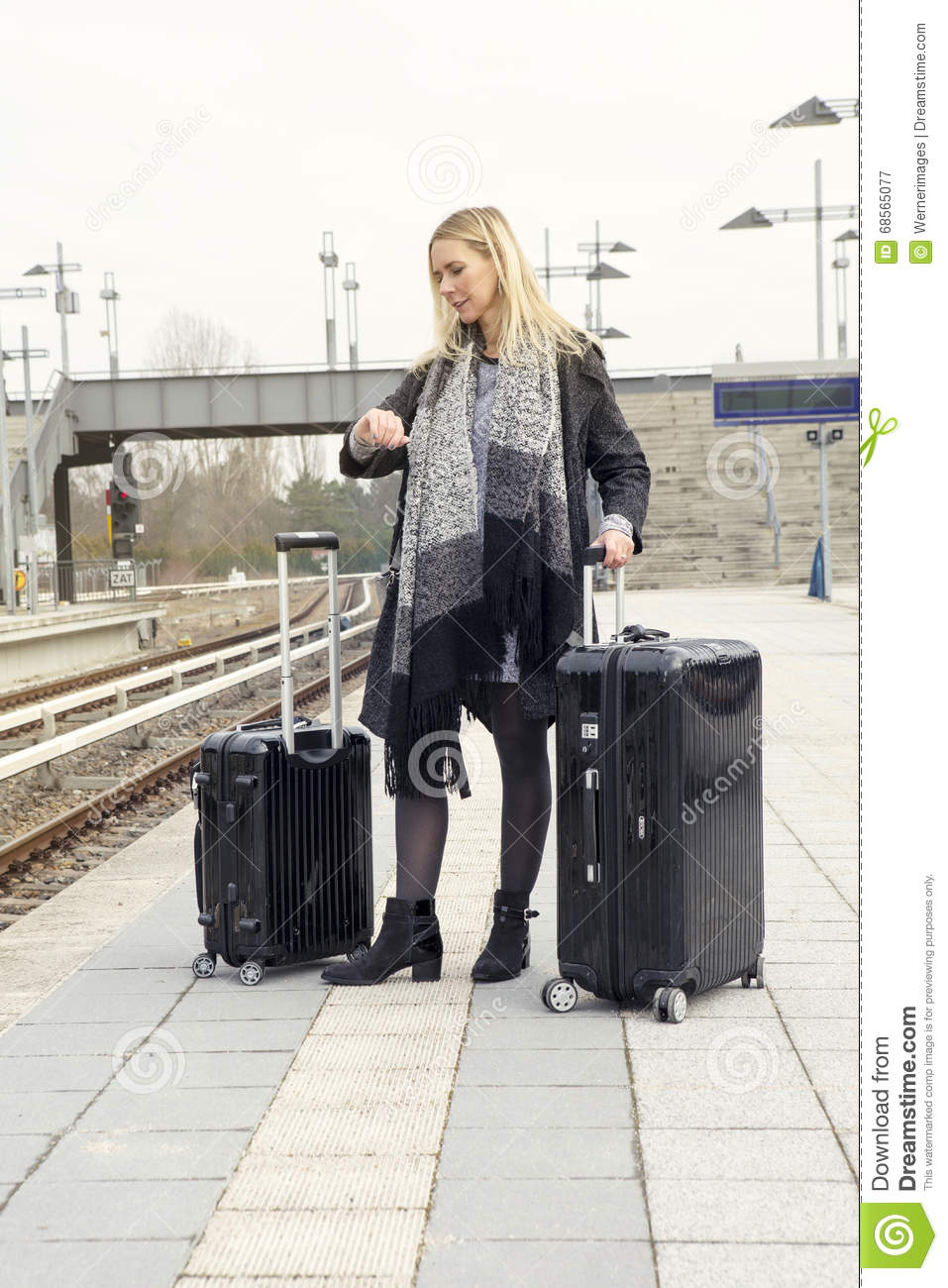 mujer-que-espera-con-las-maletas-en-la-estación-de-tren-68565077.jpg