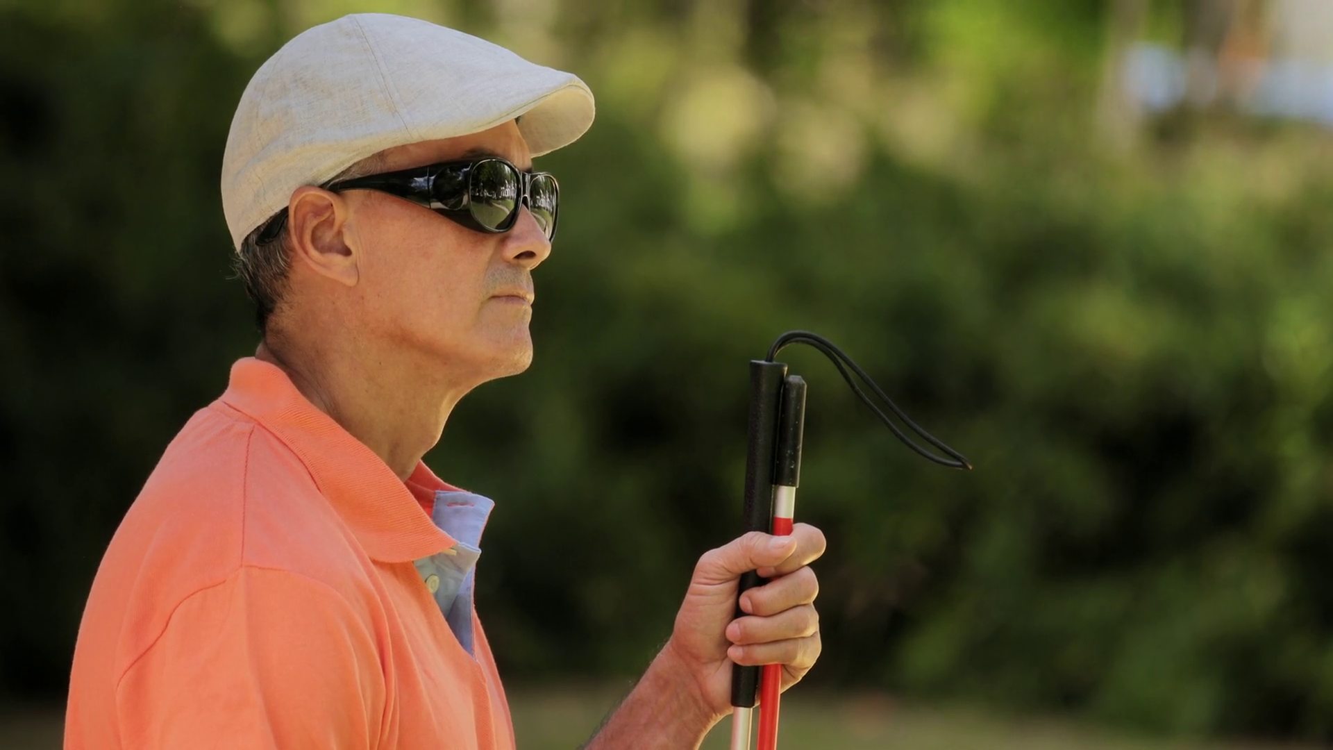videoblocks-hispanic-blind-man-latino-people-with-disability-handicapped-person-and-everyday-life-visually-impaired-man-with-walking-stick-sitting-on-bench-in-city-park-with-cars-and-traffic_hoqvlfvgb_thumbna.png