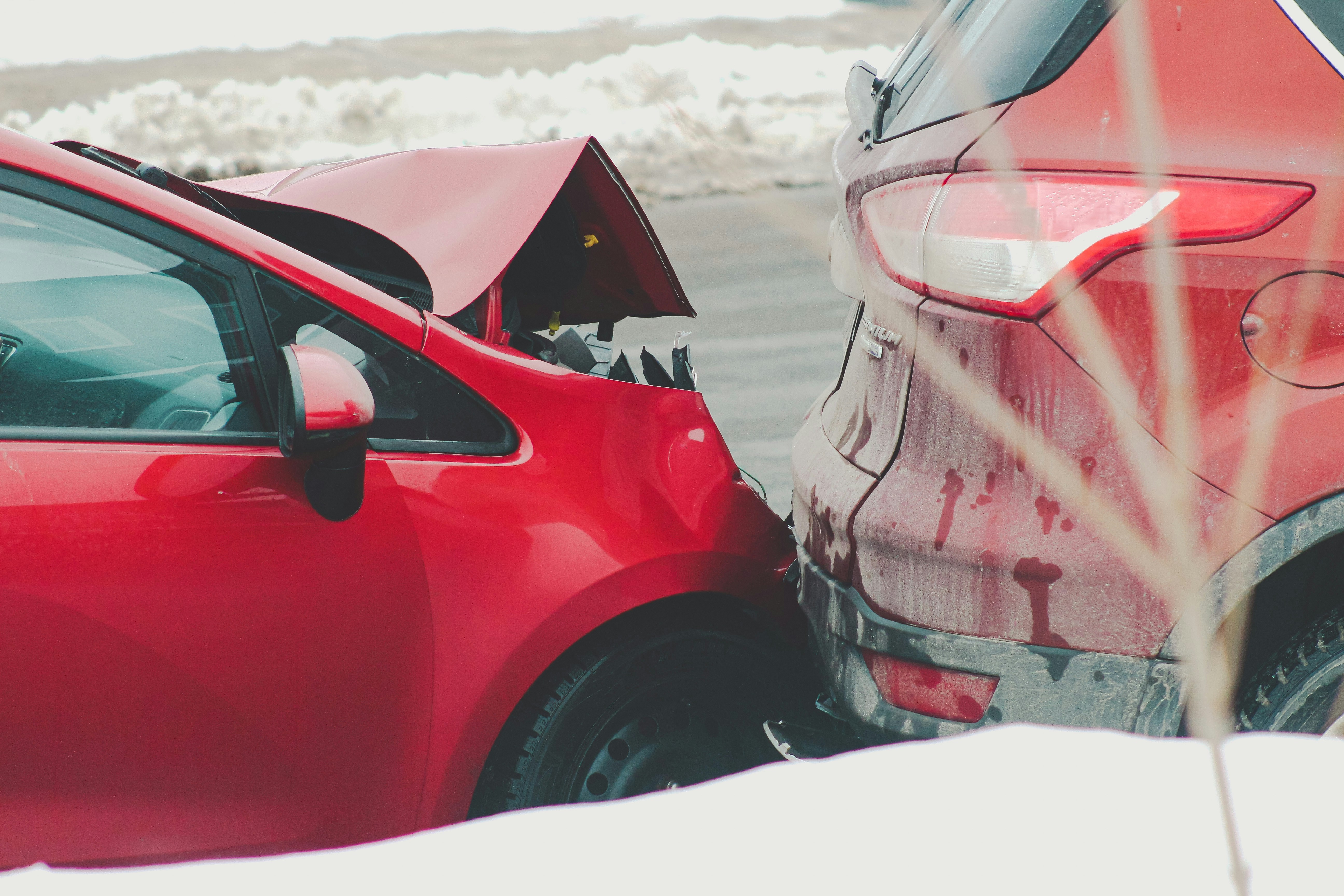 Rear-end car accident with damaged red vehicle in winter road conditions