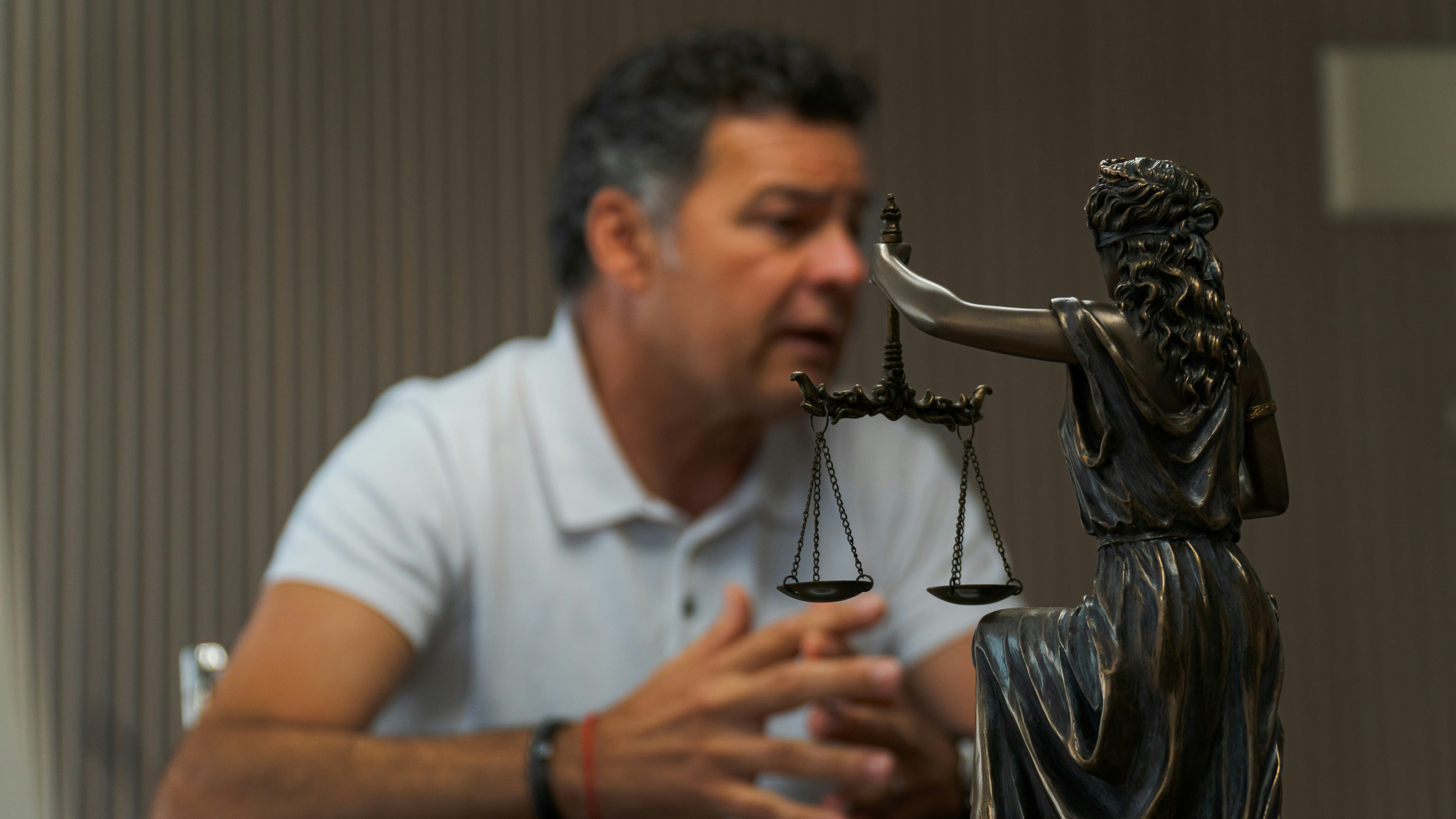 Client speaks with an attorney during a legal consultation with a Lady Justice statue in the foreground.