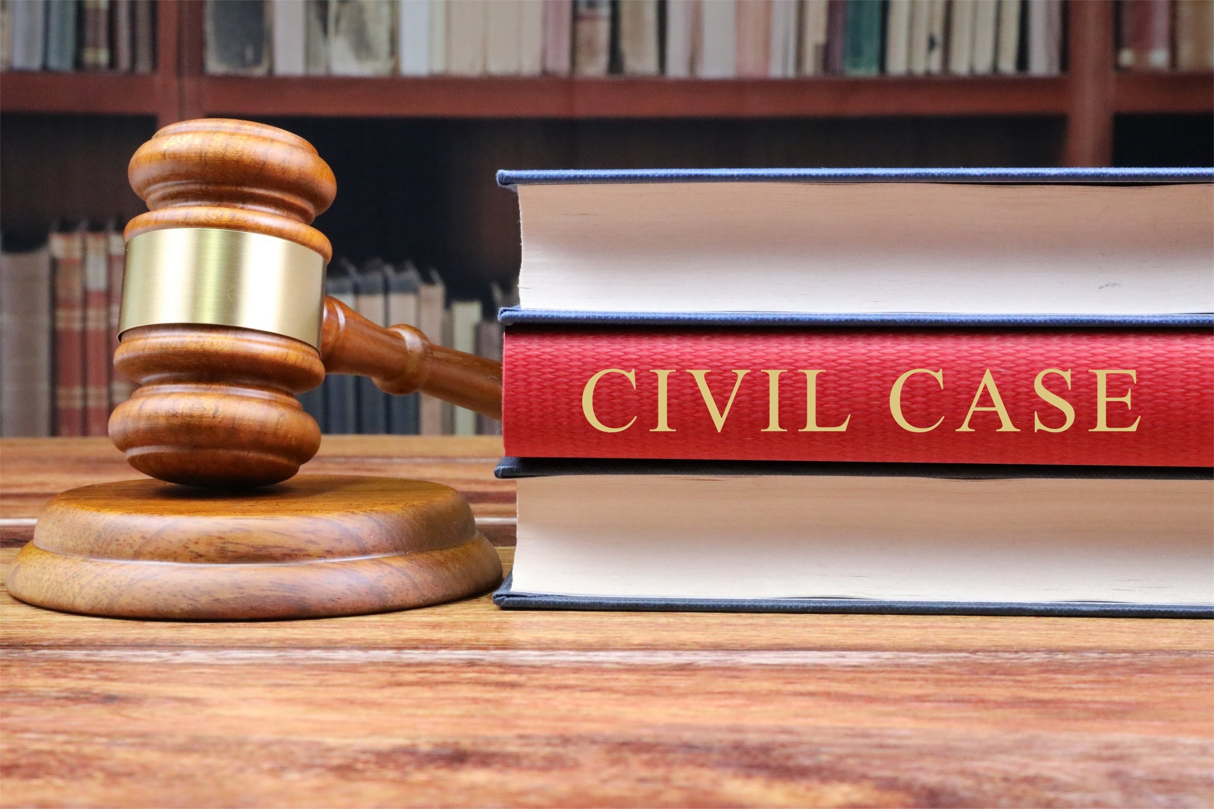A judge’s gavel rests beside stacked law books, including a red book labeled “Civil Case.”