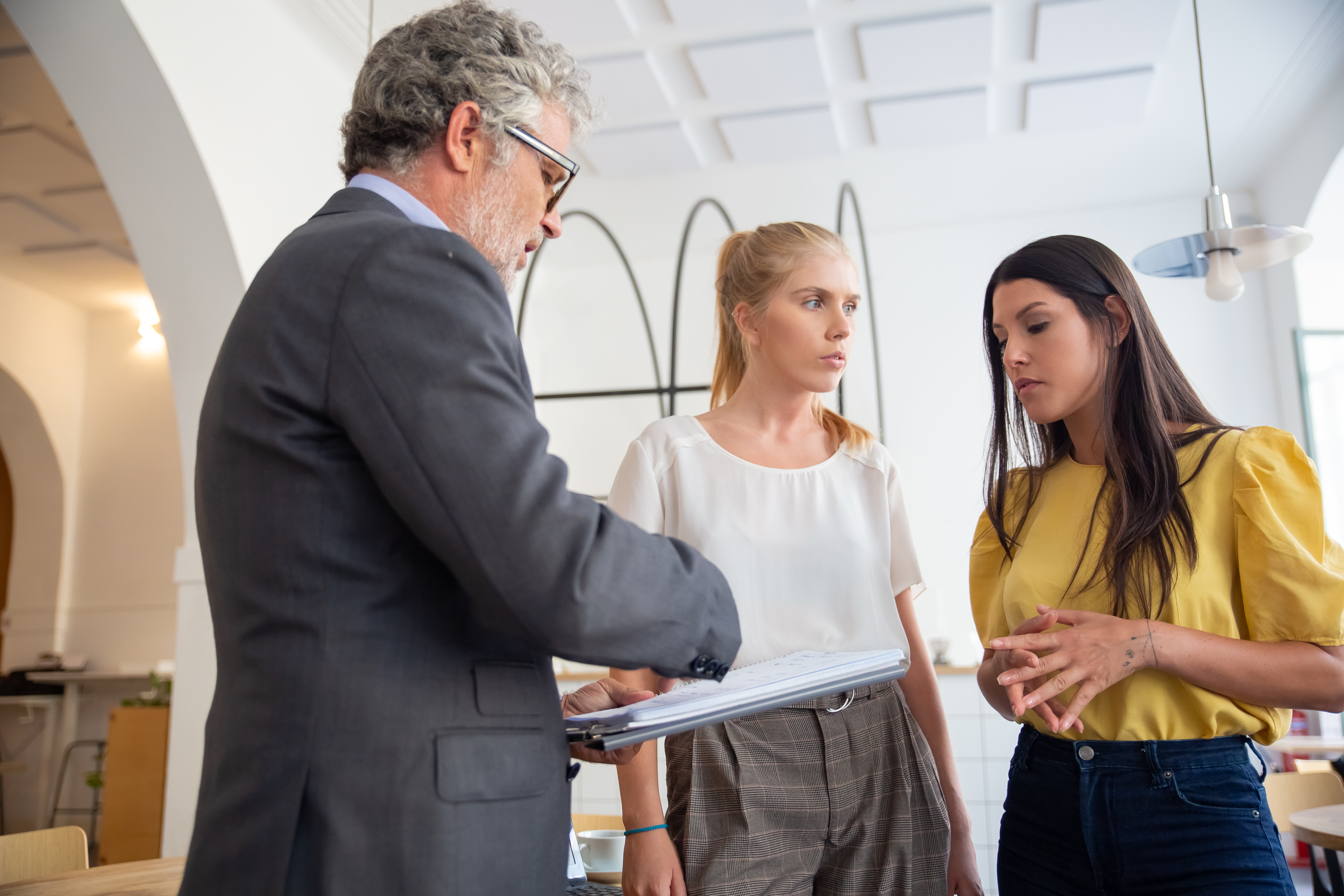 A business professional reviews documents with two women during an office consultation.