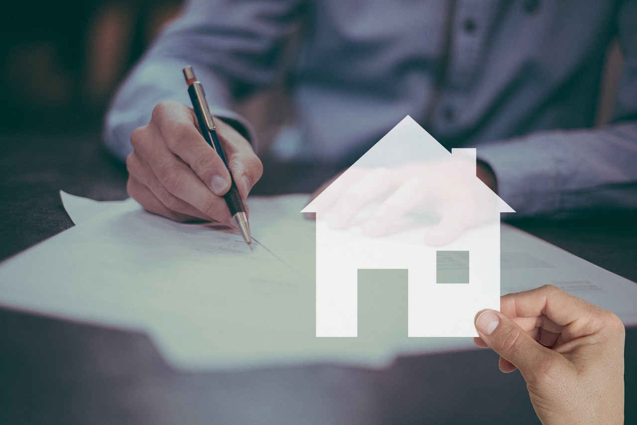 “Close-up of a hand signing documents, symbolizing a home purchase or mortgage agreement.”