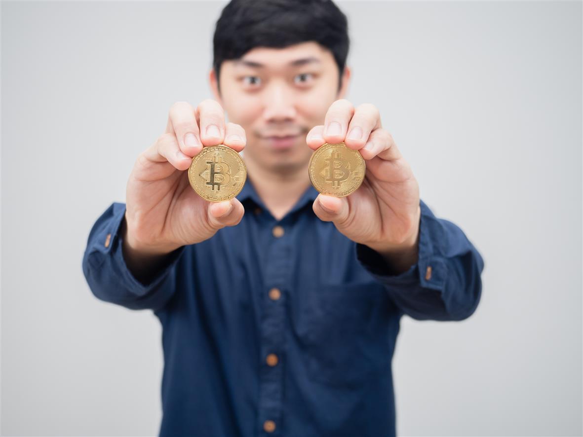 vecteezy_closeup-gold-bitcoin-in-man-hand-smile-face-white-background_16686685.jpg