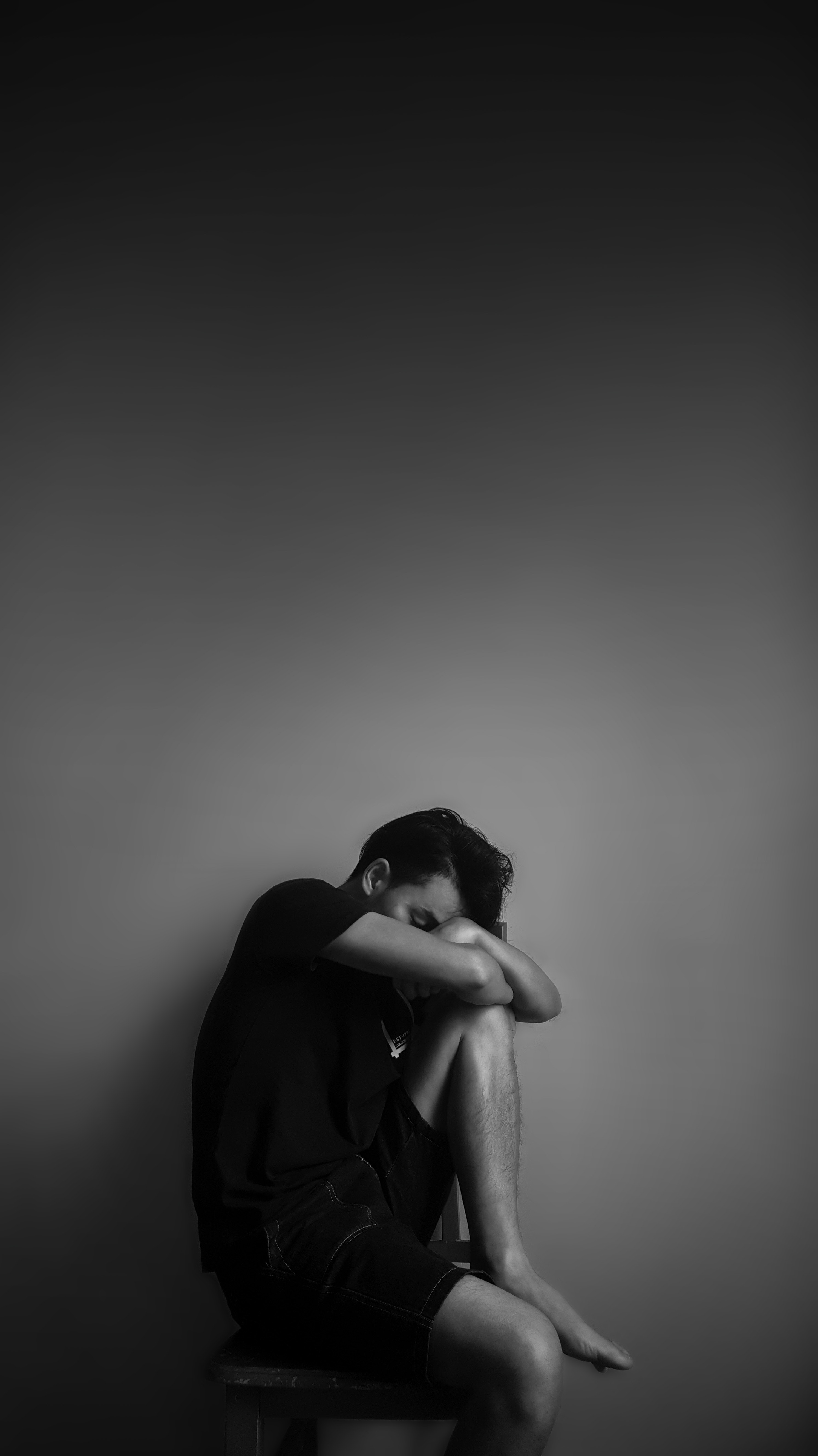 grayscale-photography-of-man-sitting-beside-wall-207129.jpg