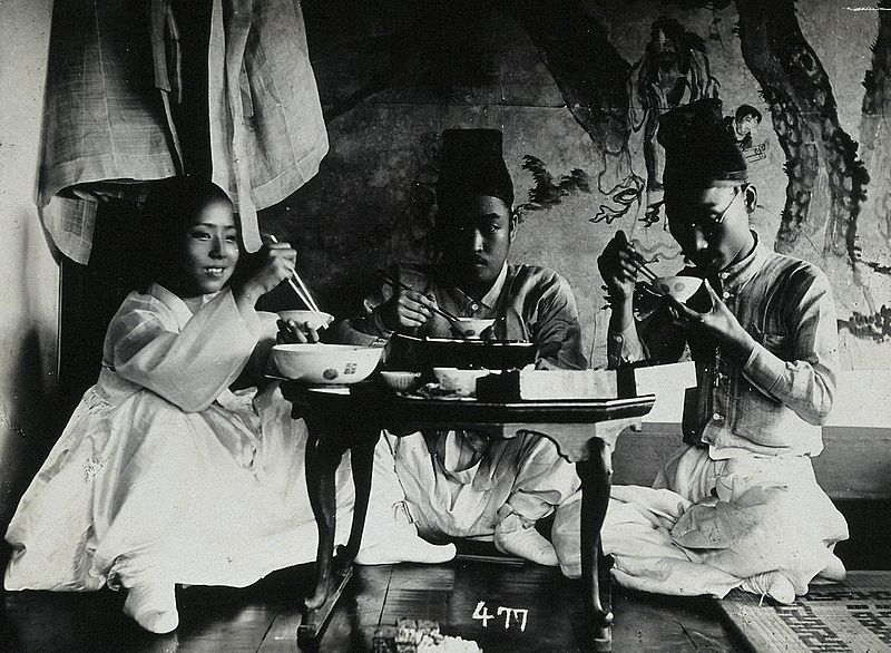 A_group_of_people_eating_a_meal,_seated_behind_a_small_table_Wellcome_V0048605.jpg