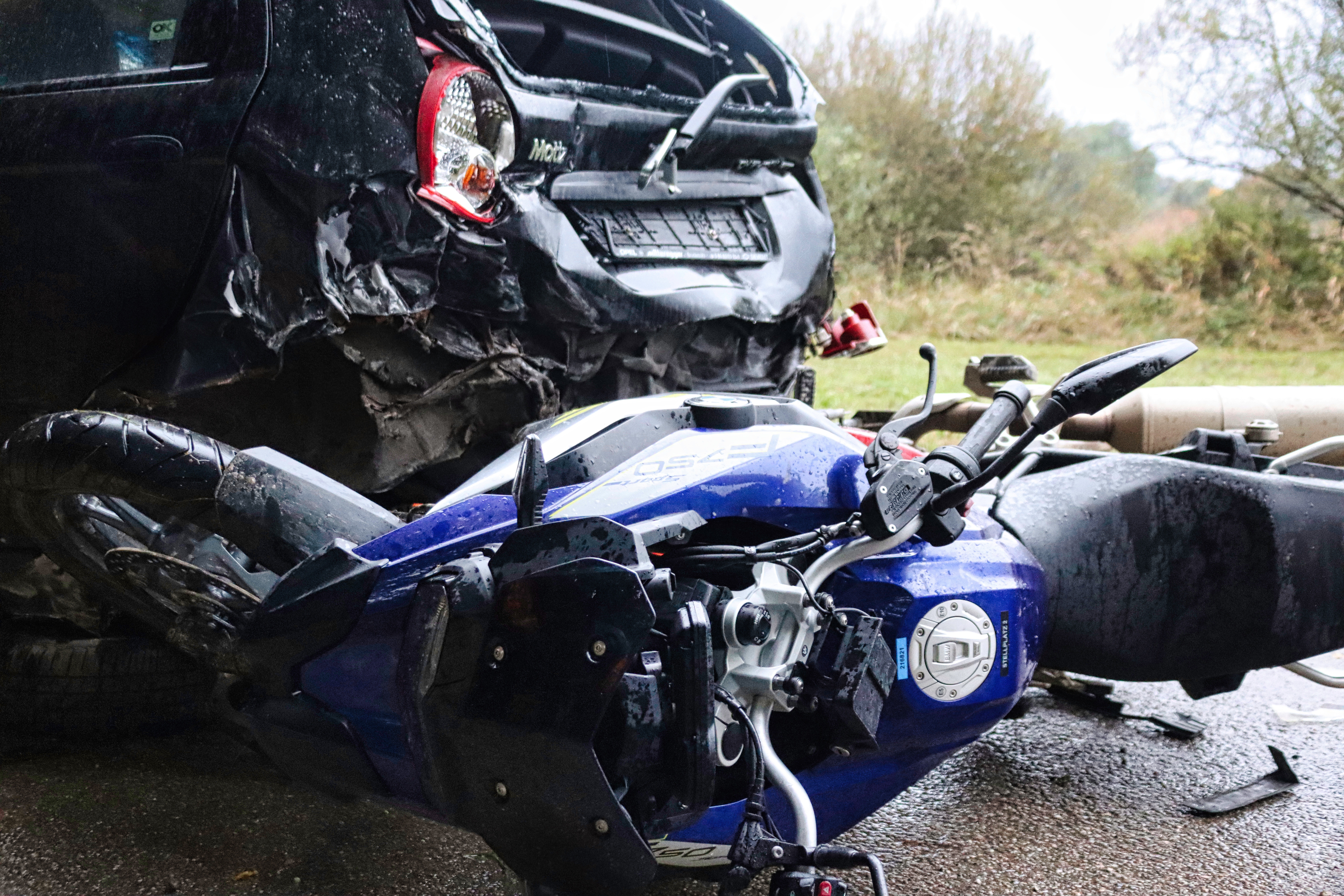 Damaged motorcycle lies on the road after a collision with a car in a serious accident scene.
