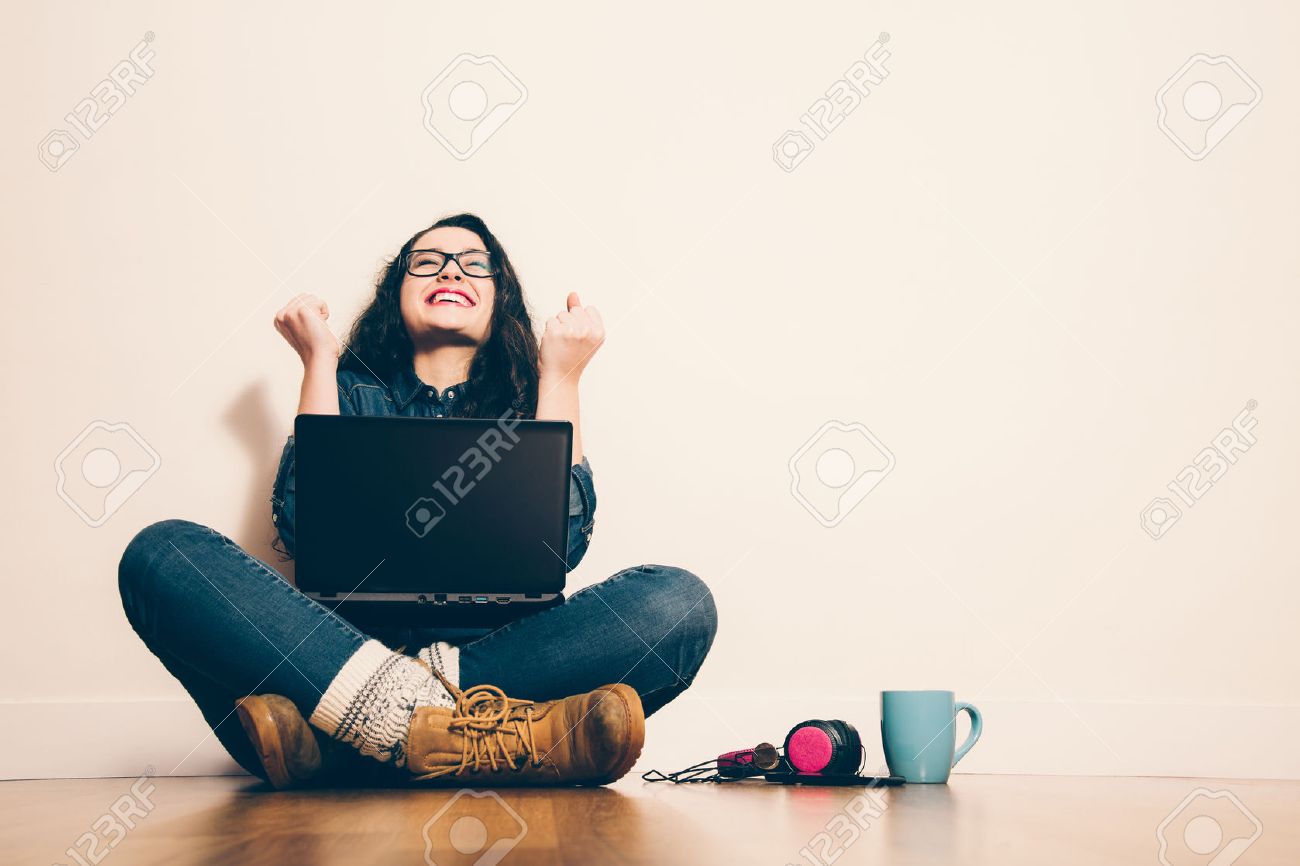 37880791-girl-sitting-on-the-floor-with-a-laptop-raising-his-arms-with-a-look-of-success.jpg